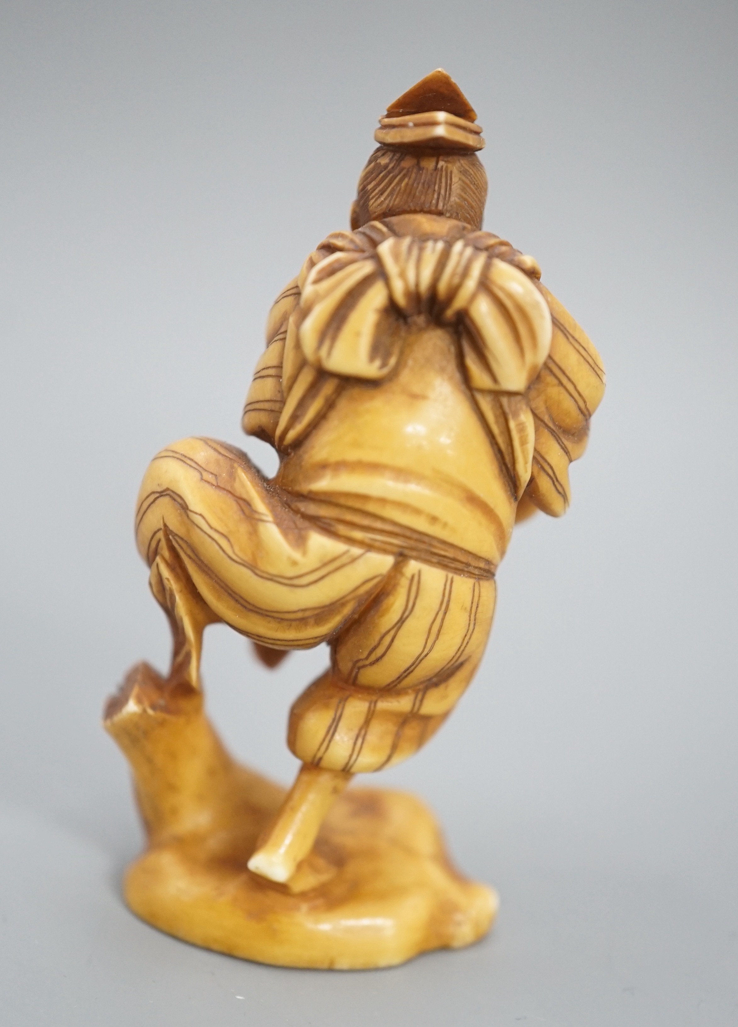 A Japanese ivory okimono of a man dancing and pouring wine from a flask, signed, Meiji period, 7cm